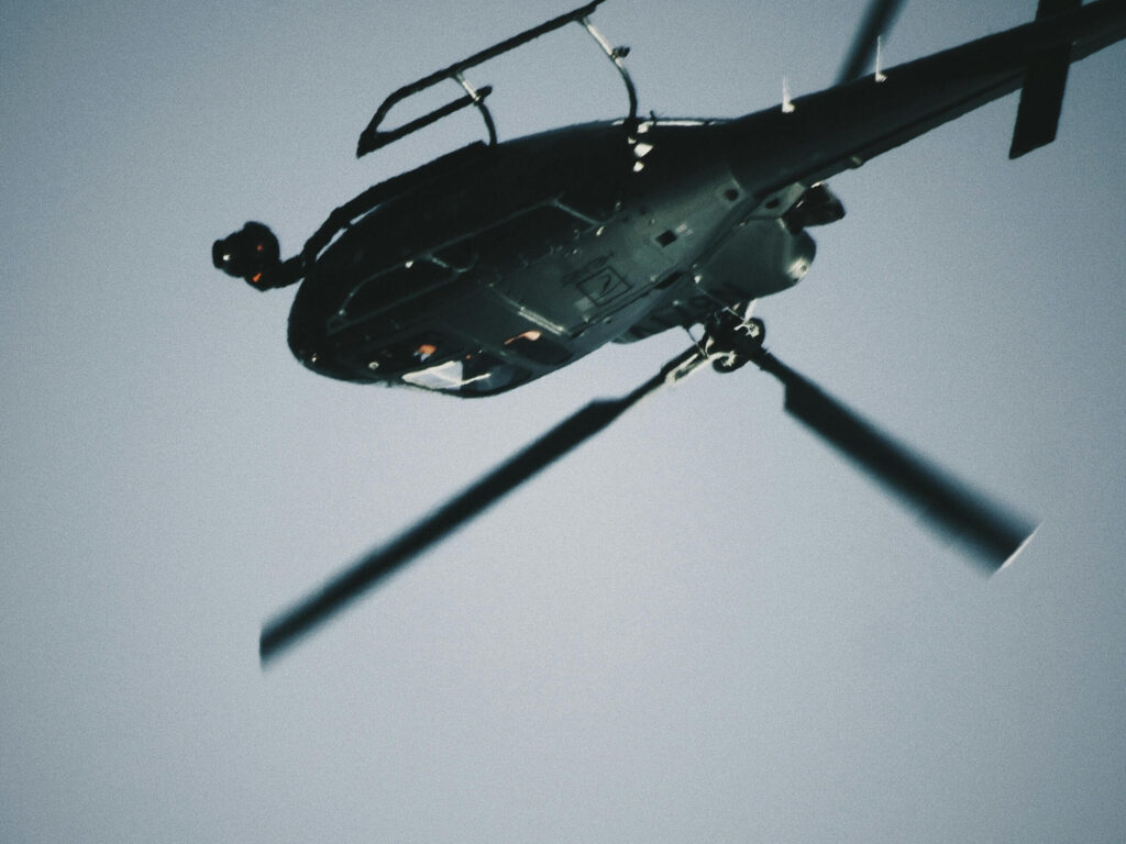 An abstract, grayscale image of a helicopter flying upside down, representing a childhood memory of political unrest in Nepal.